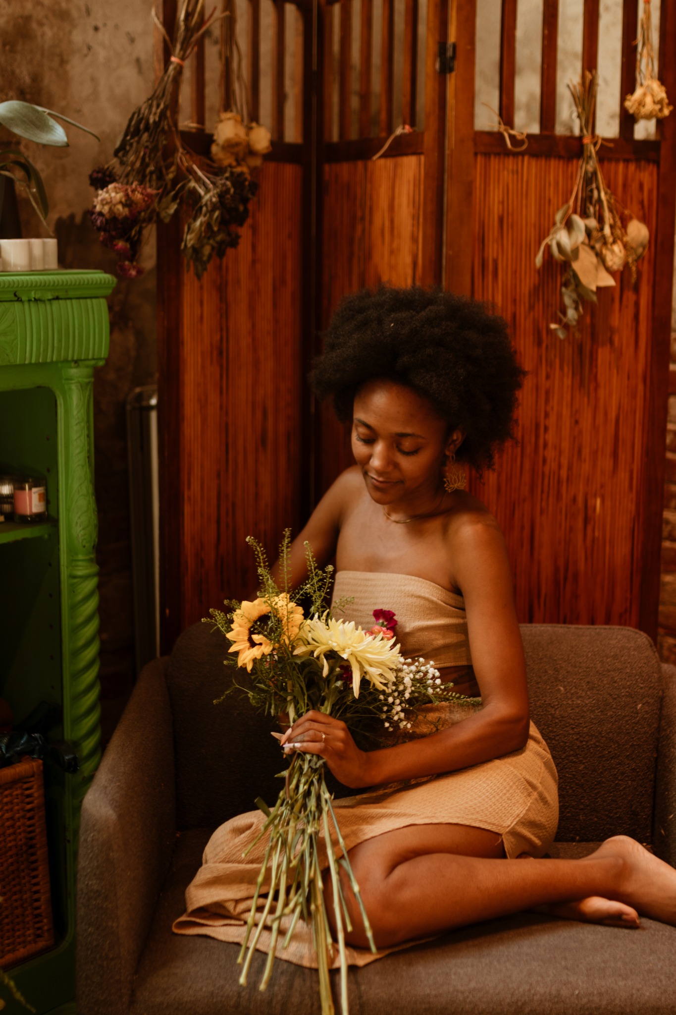 Torie Banks seated in a warm wood-paneled room arranging a bouquet of flowers